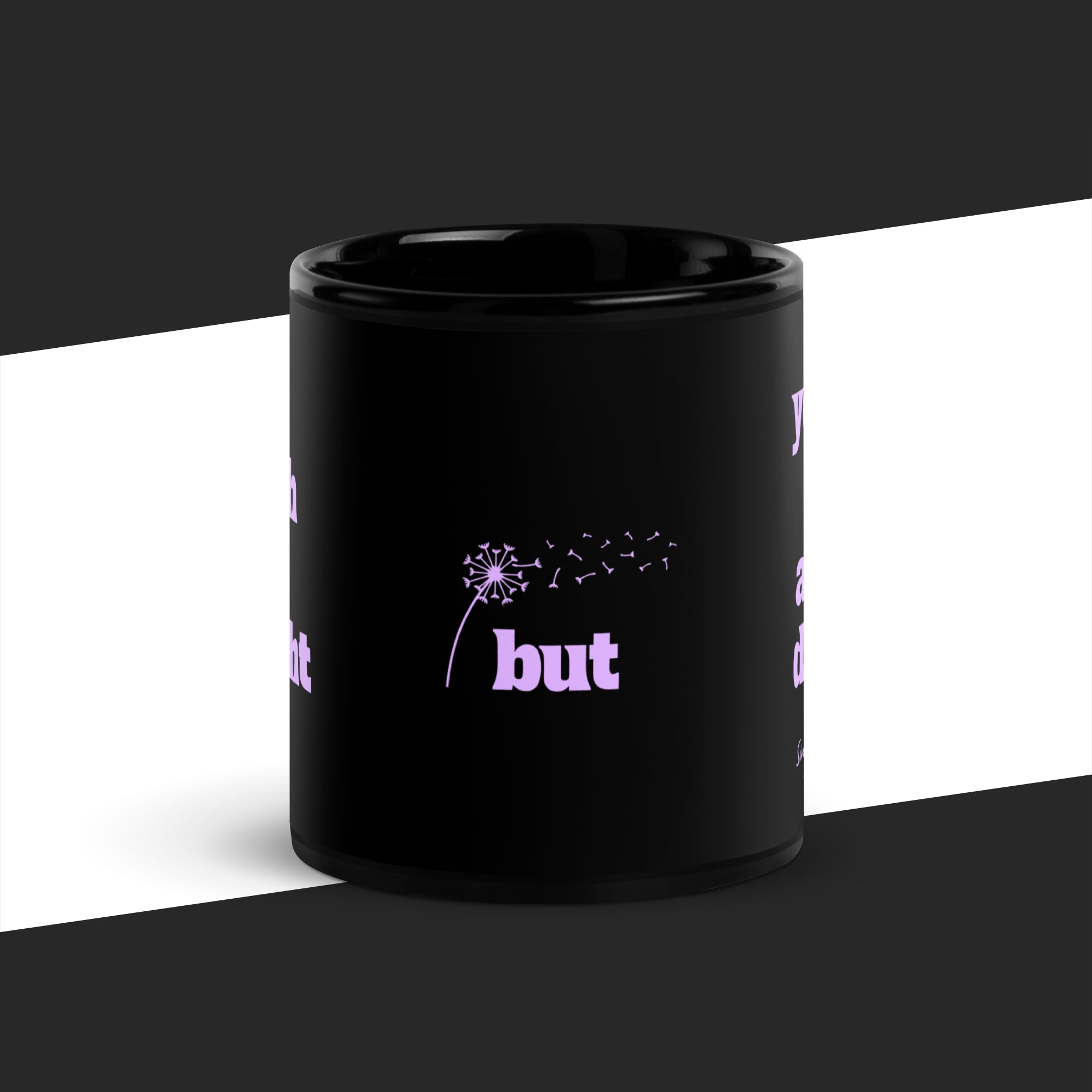 Black mug with purple text and dandelion graphic on a white and black background