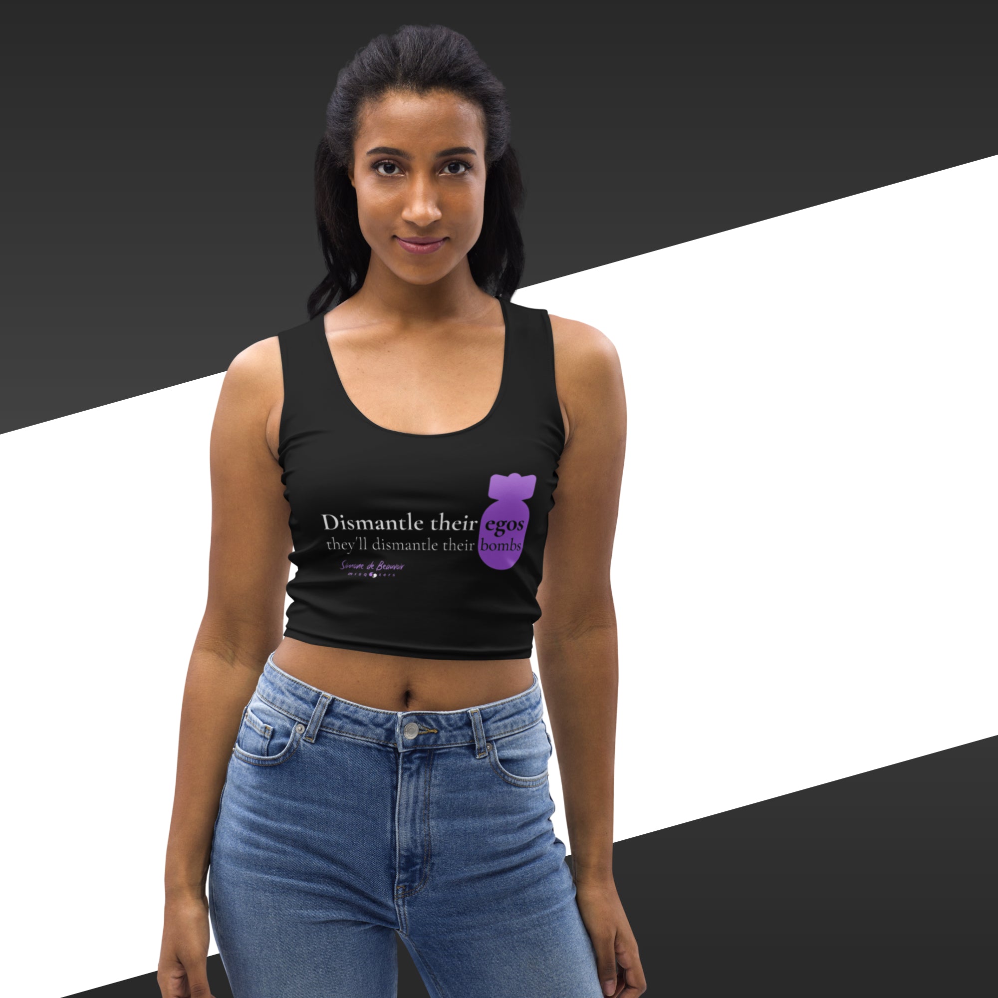 Woman wearing a black tank top with text and a graphic, standing against a black and white background.