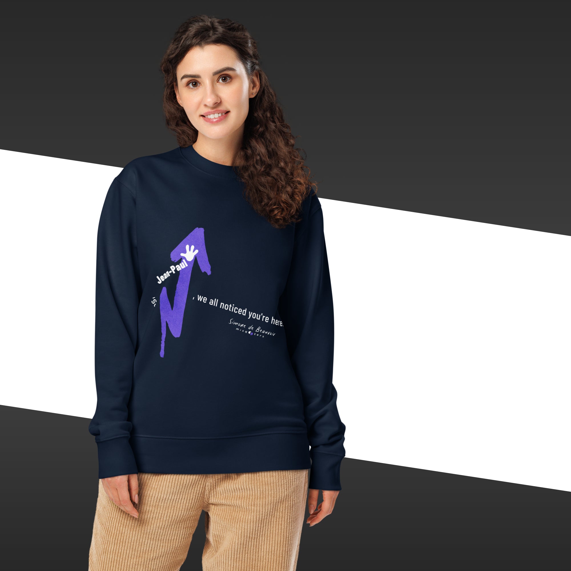 Person wearing a navy blue sweatshirt with a graphic design on a black, white, and gray striped background