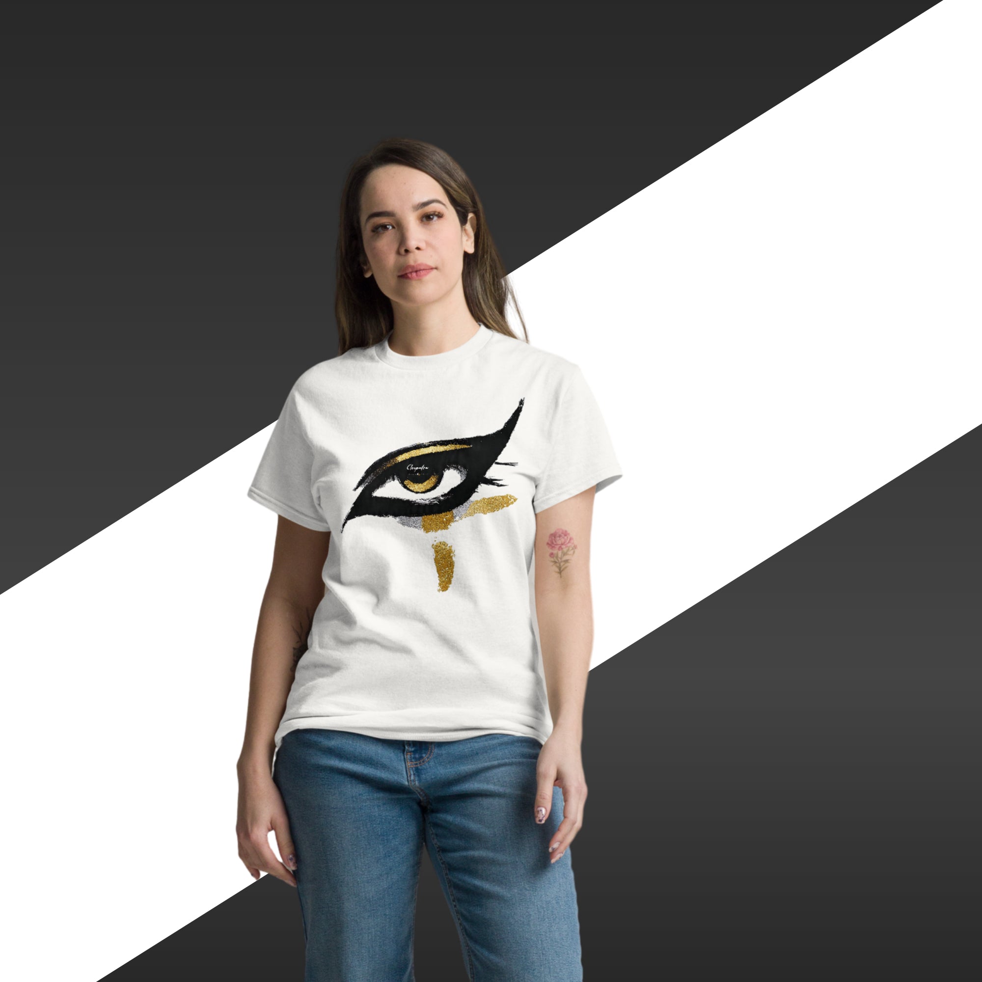 Woman wearing a white t-shirt with a black and gold eye design on a black, white, and gray background