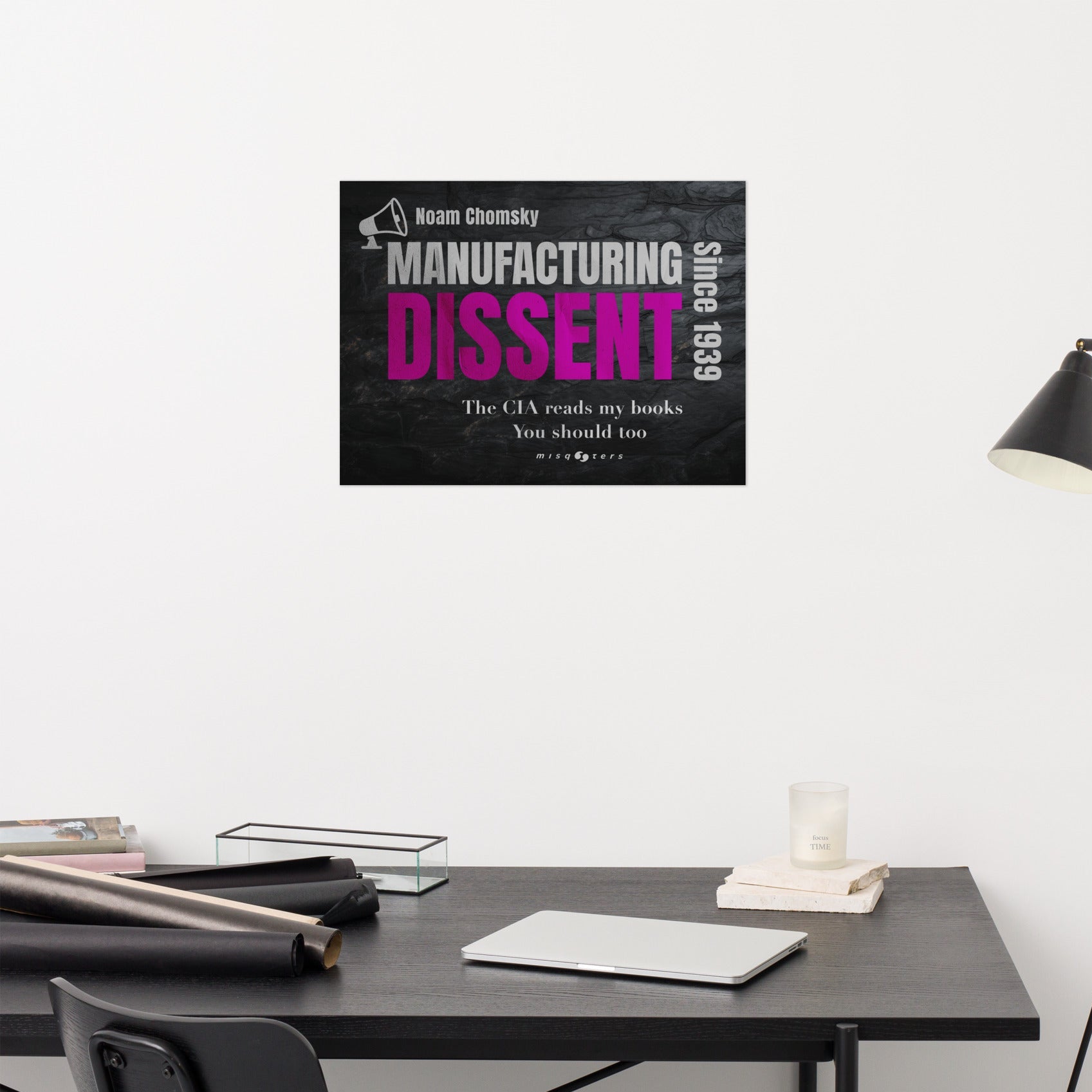 Poster of 'Manufacturing Dissent' by Noam Chomsky on a desk with a lamp in the background.