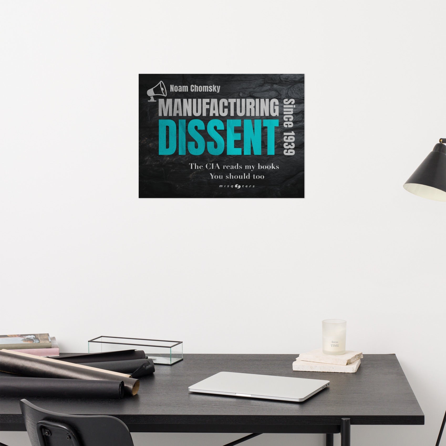 Poster of 'Manufacturing Dissent' by Noam Chomsky on a desk with a white wall background