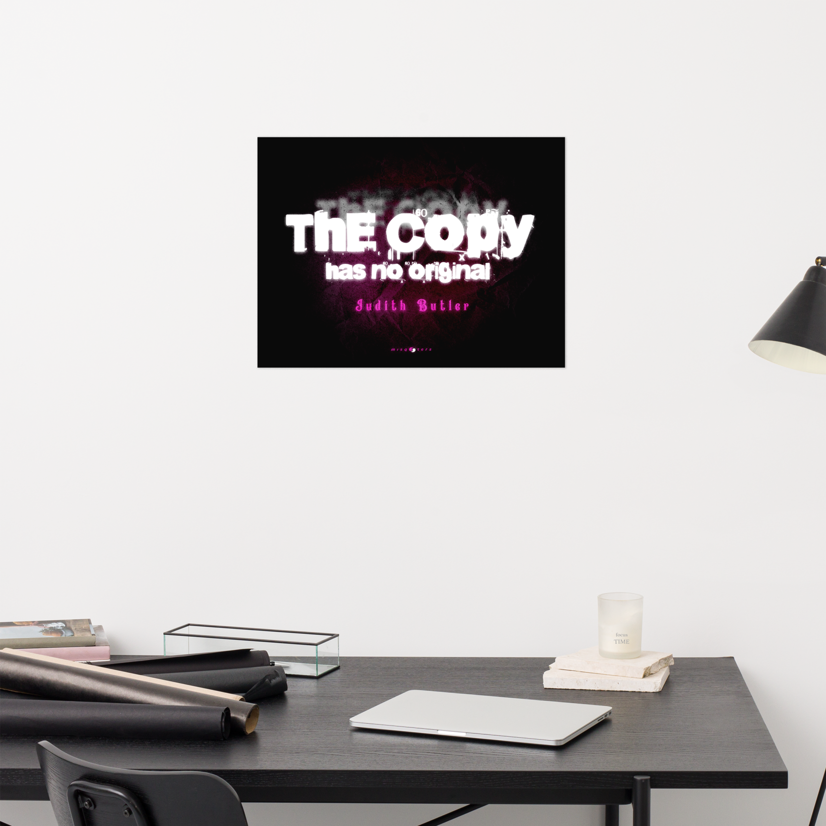 Framed artwork on a wall above a desk with office supplies.