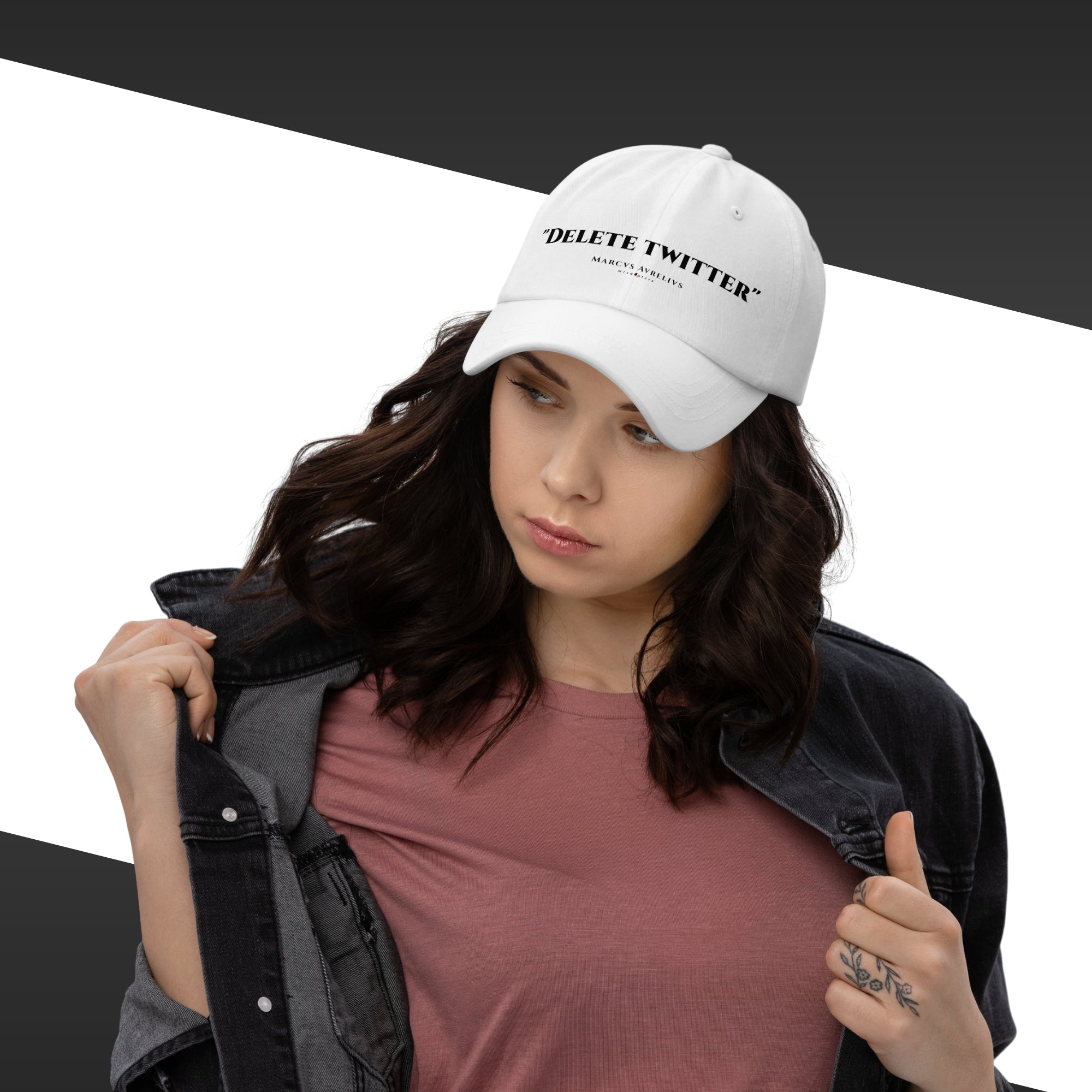 Woman wearing a white cap with text, holding a jacket against a black and white background