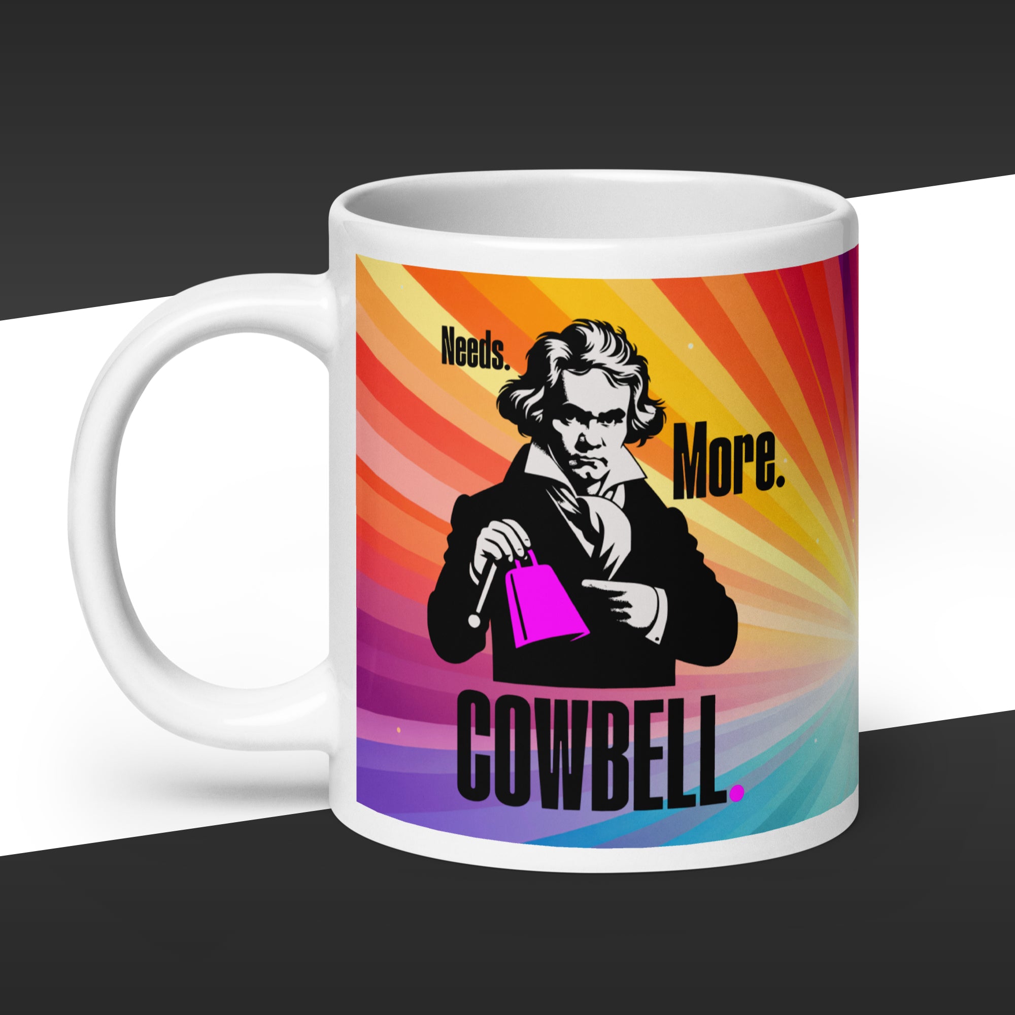 White mug with a multicolor graphic of Beethoven holding a purple cowbell and fake quote 'Needs More Cowbell' 