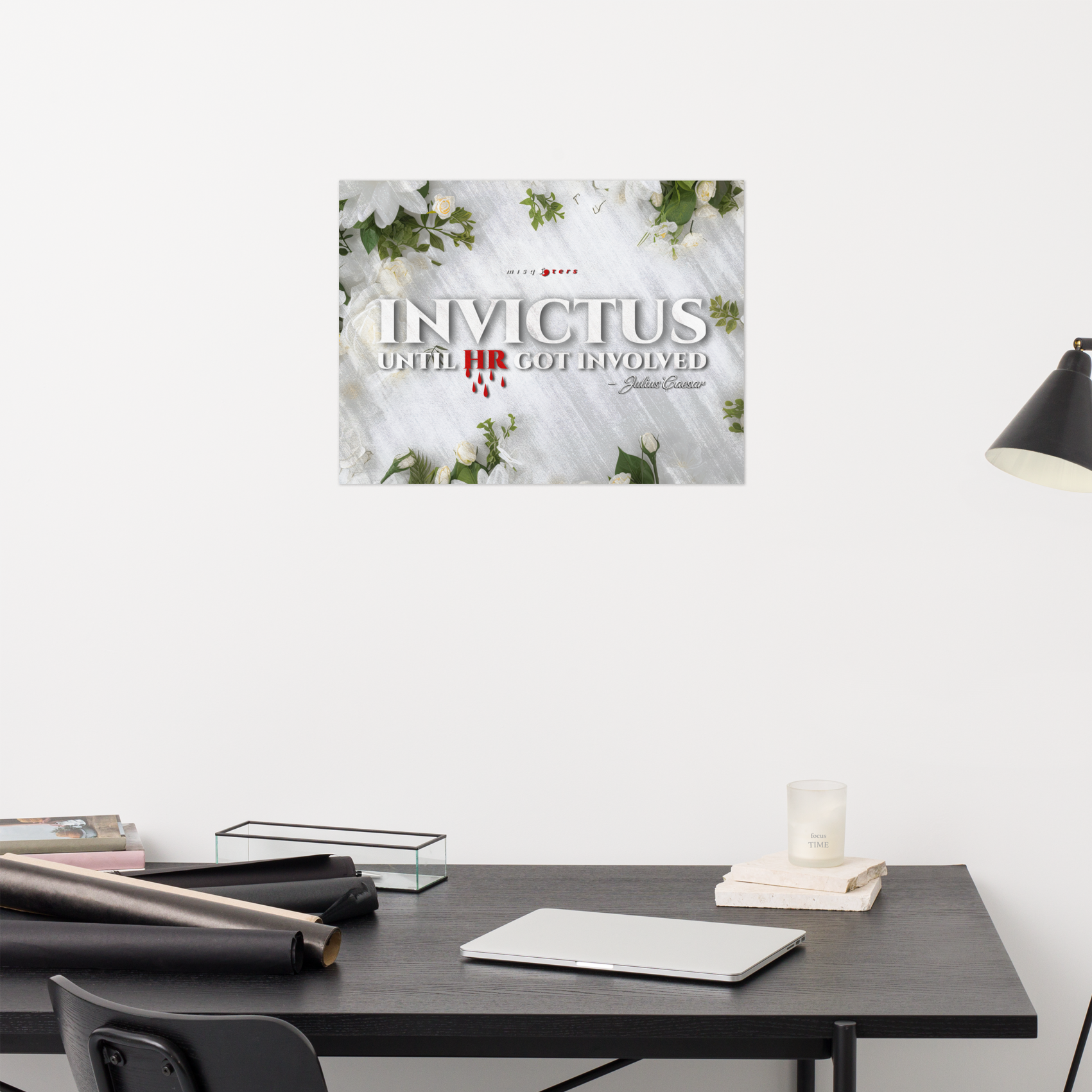Desk with a laptop and stationery items, featuring a poster titled 'Invictus' on the wall.
