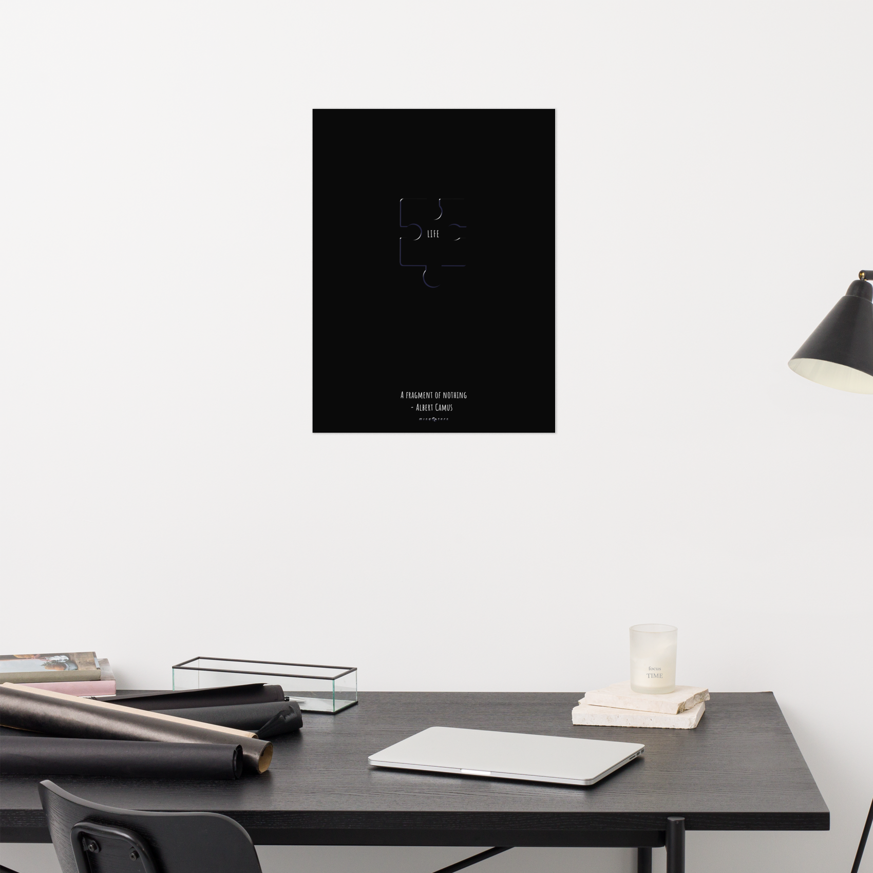 Black poster on a white wall above a desk with office supplies.