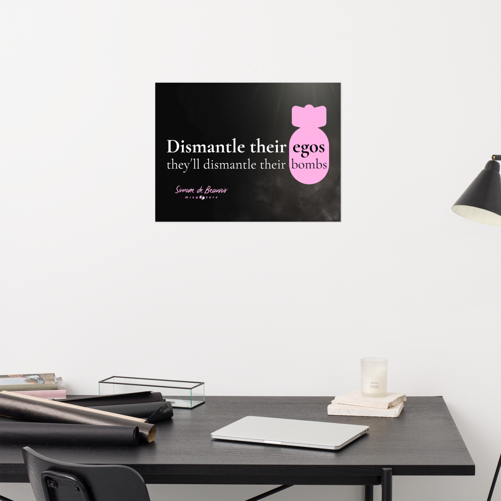 Modern office setup with a desk, chair, and lamp against a white wall with a feminist poster from simone de beauvoir.