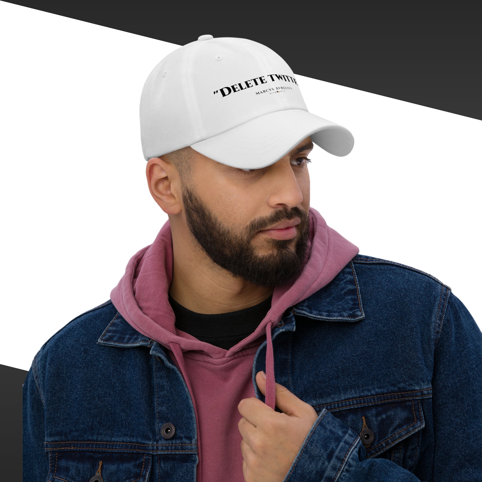 Man wearing a white cap with text, pink hoodie, and blue denim jacket on a black and white background